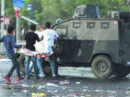 Manifestantes en la plaza principal de Dirayambakir, atacan un vehículo policial tras suscitarse dos explosiones. AFP /