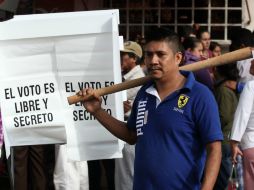 Un hombre armado con un gran palo de madera permanece cerca de una casilla electoral de Tixtla, Guerrero. AP / F. Márquez