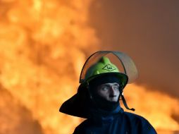 Los bomberos luchan contra el fuego sin poder dominarlo y temen que las llamas alcancen un depósito petrolero vecino. AFP / S. Supinsky