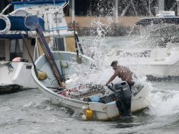 Un hombre trata de controlar su bote, en medio de un oleaje intenso y fuertes vientos ocasionados por la tormenta tropical ''Carlos''. AFP / P. Pardo