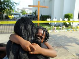 Una mujer abraza a su pequeña hija mientras observa la parte frontal de la iglesia donde ocurrió el tiroteo. AP /