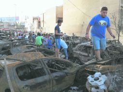 Curiosos revisan la escena de un ataque del Estado Islámico, cerca de Bagdad, en el que murieron 14 personas. AFP /
