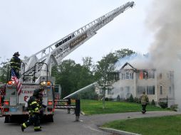 Los bomberos combaten el incendio en la casa que está 'completamente envuelta' por el fuego. AP / M. Stockwell