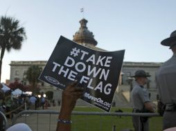 Una mujer sostiene un cartel mientras espera que la bandera confederada deje de ondear frente al edificio del Capitolio en Charleston. AP / J. Bazemore