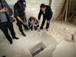 En cuclillas, Arely Gómez González, titular de la PGR, observa el orificio por donde 'El Chapo' Guzmán habría escapado. NTX /