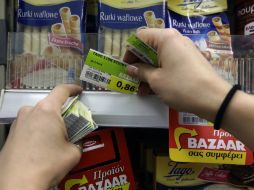 Un empleado de una tienda remplazo los precios de algunos productos luego del incremento del IVA en Grecia. AP / T. Stavrakis