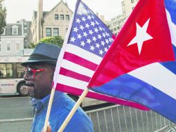 Nueva era. Un hombre ondea las banderas cubana y estadounidense, frente a la embajada de Cuba en Washington. AFP /