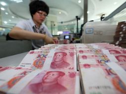 Una cajera cuenta yuanes en un banco en Lianyungang, en la provincia de Jiangsu. China devaluó su moneda en casi dos por ciento. AFP /