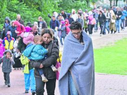 Migrantes caminan hacia una estación en donde pueden conseguir la primera asistencia para su refugio. AP /