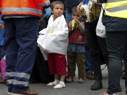 Un niño refigiado con los pies vendados espera junto a su familia para ser llevados a un centro de acogida a su llegada a Múnich. EFE / A. Warmuth