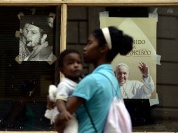 Una mujer con su bebé pasa delante de un cartel alusivo a la visita del Pontífice. AFP / F. Monteforte
