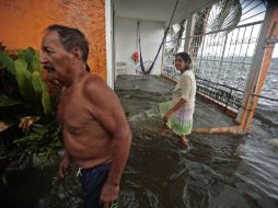 Una pareja permanece en su casa inundada debido al desbordamiento de la laguna de Coyuca en Acapulco. AFP / P. Pardo