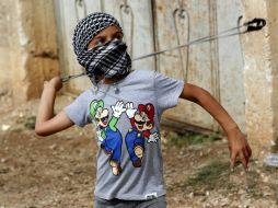 Un niño palestino lanza piedras contra las tropas israelíes en Qadomem, Cisjordania. EFE / A. Badarneh