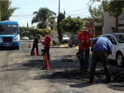 Varios hombres realizan labores de bacheo en calles de la Colonia Seattle. EL INFORMADOR / A. Hinojosa