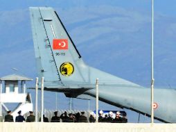 Oficiales turcos saludan ante el cuerpo del soldado ruso fallecido en el avión derribado por Turquía. AP /