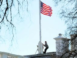 Luto nacional. Un trabajador de la Casa Blanca iza la bandera a media asta en señal de duelo. AP /