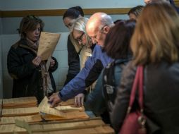 Los primeros votantes seleccionan sus papeletas antes de ejercer su derecho al voto, en el colegio Claret. EFE / E. Naranjo