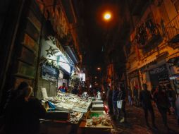 Clientes compran diversos alimentos marinos en el tradicional mercado que permanece abierto en el centro de Nápoles. AFP / C. Hermann