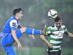 Juego peligroso. El mexicano Héctor Herrera le enseña los tachones al portugués Joao Pereira. AFP /