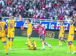 El delantero de Chivas, Ángel Saldívar, se “escapa” de la protesta que hacían los jugadores de Tigres por una infracción en el juego. EL INFORMADOR / R. Tamayo