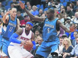 Carmelo Anthony (centro), de los Knicks de Nueva York, ante la marca de dos jugadores de los Timberwolves de Minnesota. AP / J. Mone