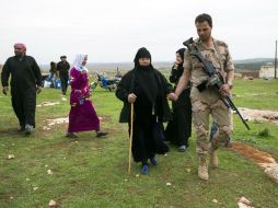 Soldado sirio acompaña a una anciana a recibir ayuda humanitaria rusa. La tregua pactada el pasado 27 de febrero redujo la violencia. AP / P. Golovkin