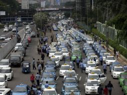 Taxistas permanecen junto a sus vehículos durante la manifestación que colapsó varias calles. EFE / B. Indahono