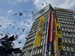 Decenas de personas lanzan falsos billetes en el aire durante una protesta contra el blanqueo de capitales, en Viena. EFE / C. Bruna