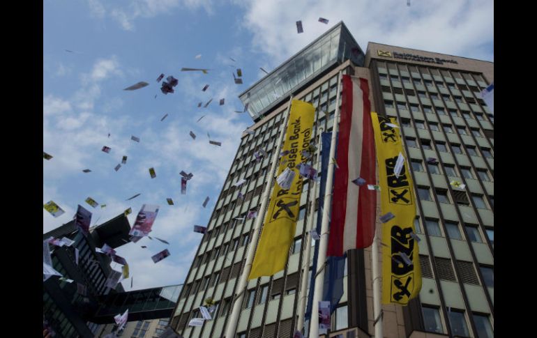 Decenas de personas lanzan falsos billetes en el aire durante una protesta contra el blanqueo de capitales, en Viena. EFE / C. Bruna