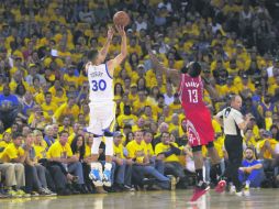 Stephen Curry (izq) dispara ante la tardía llegada de James Harden, ayer en la victoria de los monarcas, que van por el bicampeonato. AP / M. J. Sánchez