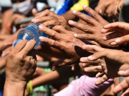 Carencias en las calles. Residentes reciben agua potable en Manta. AFP / L. Acosta