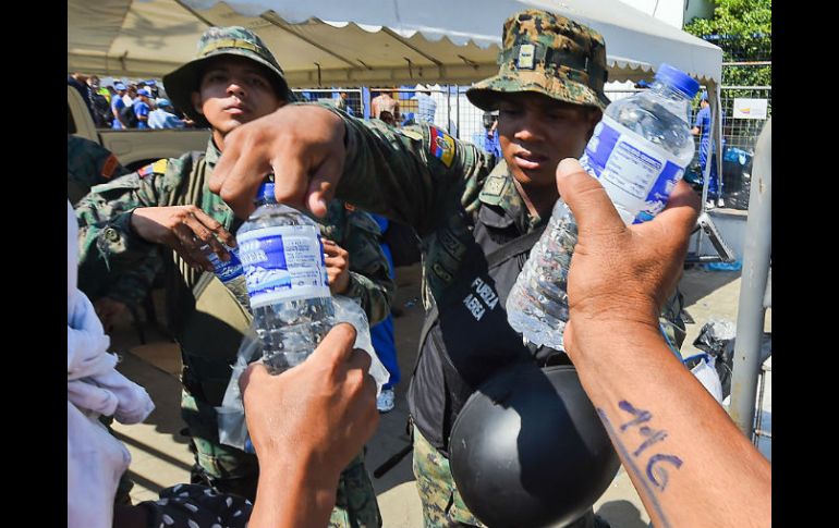 Militares reparten botellas de agua potable a los damnificados; surtir del vital líquido a la población es primordial. AFP / L. Acosta