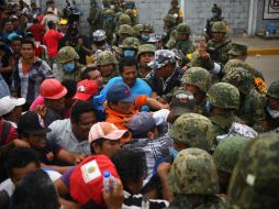 Desesperados por la falta de información sobre sus familiares, hombres y mujeres arremeten contra efectivos de Sedena. EFE / A. Hernández