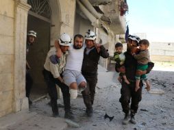 Voluntarios evacuan a un hombre lisiado y a varios niños de un edificio dañado por los recientes bombardeos. AFP / A. Alhalbi