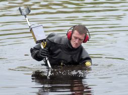 Buzos de la policía estatal peinaron un estanque cerca del lugar donde el policía victimado había detenido al vehículo. AP / R. Cinclair