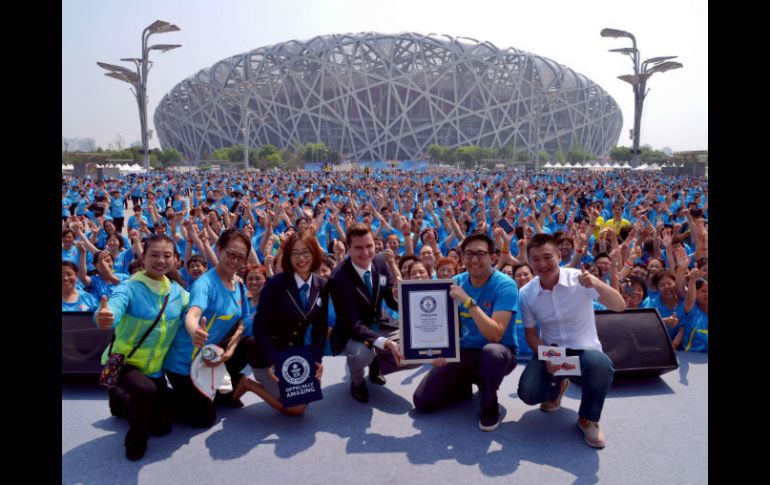 Participantes posaron con representantes de Guinness delante del icónico estadio olímpico conocido como Nido de Pájaro. AP / Chinatopix