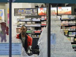 El trabajador de una tienda de autoservicio observa los daños ocasionados por el tiroteo. AP / L. Otero