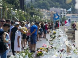 Una multitud de personas se detiene ante las flores y velas depositadas en el Paseo de los Ingleses. EFE / O. Anrigo