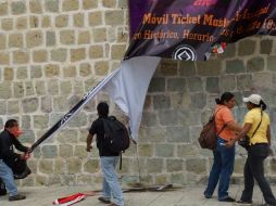 Los maestros arrancan una lona alusiva a las fiestas de la Guelaguetza. SUN / E. Hernández