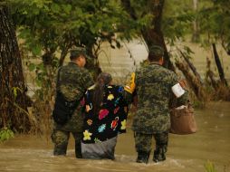 Dos soldados mexicanos ayudan a una mujer luego de una inundación ocasionada por ''Earl''. SUN / L. López
