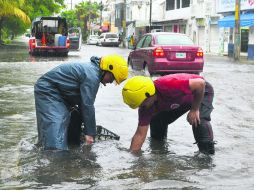 Elementos de Protección Civil de Quintana Roo destapan una alcantarilla para terminar con una inundación. NTX /