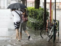 Dos personas agarran sus paraguas para protegerse contra la lluvia y el fuerte viento. EFE / C. Jue