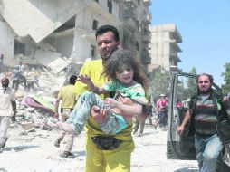 Salvamento. Un hombre lleva a un menor tras ser rescatado de las ruinas por el ataque en Alepo. AFP /