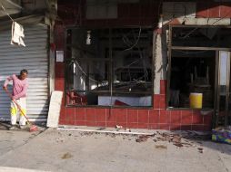 El propietario de un negocio limpia los vidrios rotos y pedazos de ladrillo que quedaron tras el estallido. AP / K. Kadim