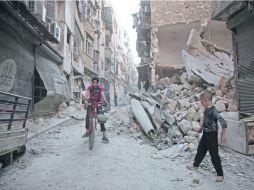 Dos menores van por una calle de Karm al-Jabal, destruido por los ataques armados. AFP /