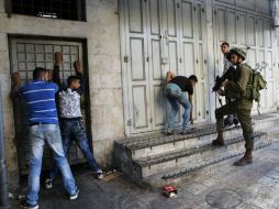 Varios agentes de la policía fronteriza israelí detienen a un grupo de palestinos en las calles de la ciudad cisjordana de Hebrón. EFE / A. Al Hashlamoun