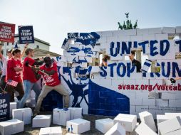 Un grupo de activistas construye un muro en Berlín con la cara de Donald Trump y luego lo derriban. AFP / O. Andersen