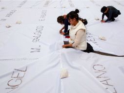 Los nombres fueron grabados con ceniza sobre cuadros de tela blanca unidos con hilos de colores. AFP / J. M. Gomez