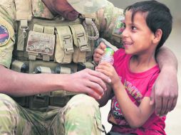 Un miembro de las fuerzas iraquíes da jugo a un niño en la aldea de Umm Mahahir luego de que el Ejército desplazara a los yihadistas. AFP /