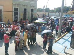 Las personas están reunidas fuera del módulo en el cruce de Juan Álvarez y Liceo, donde están amontonadas bajo el sol. EL INFORMADOR / R. Bobadilla